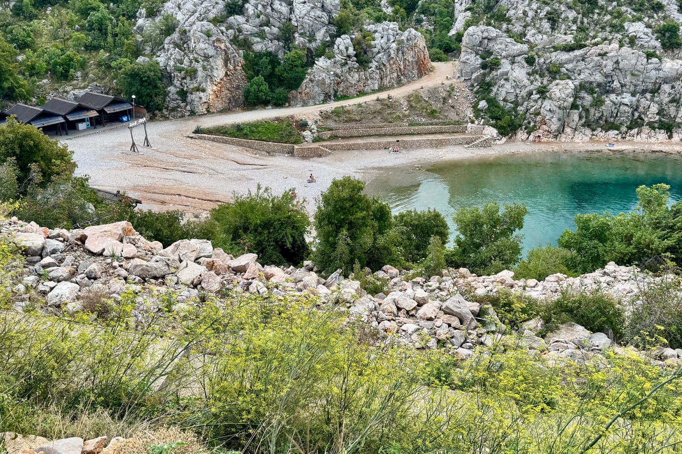 Uvala u Karlobagu s prilaznim putem koji se spušta do šljunčane plaže.
