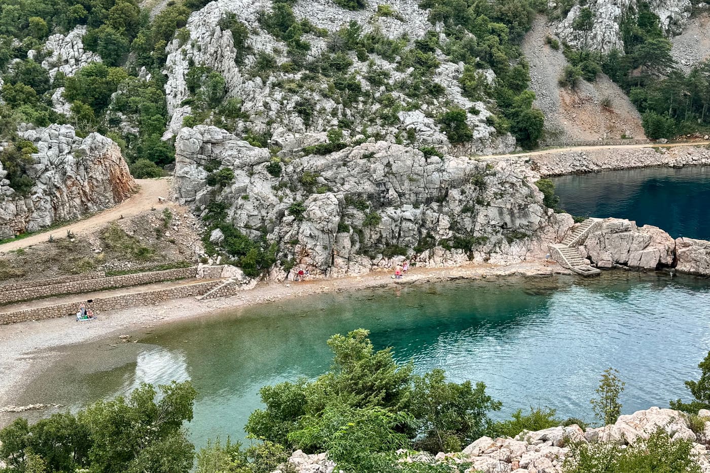 Plitka zelena voda uvale u Karlobagu i kamene stube na rubu.