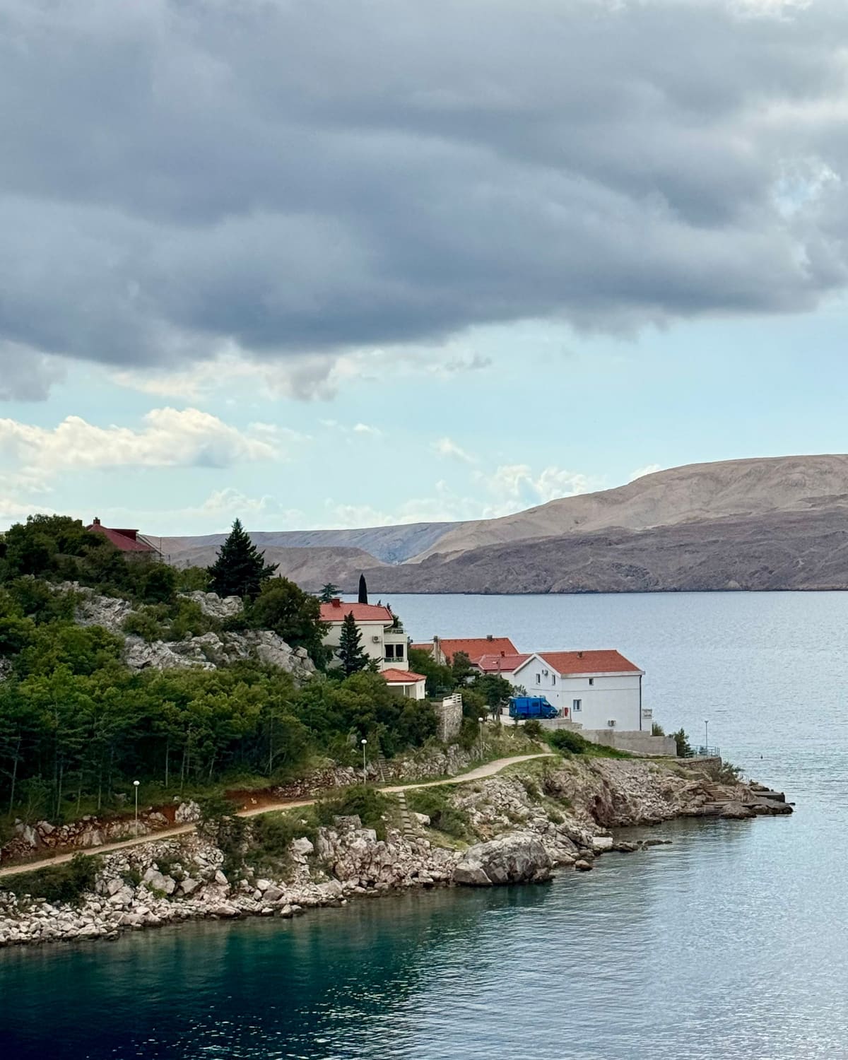 Karlobag: kuće crvenih krovova na obali, a preko kanala goli greben otoka Paga.